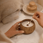 Hands lighting a Warmelle Coco Haven coconut shell candle