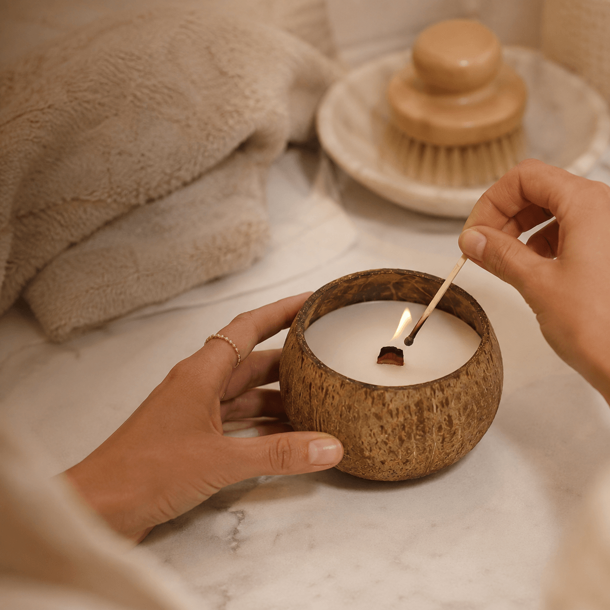 Hands lighting a Warmelle Coco Haven coconut shell candle