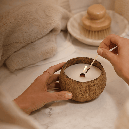 Hands lighting a Warmelle Coco Haven coconut shell candle