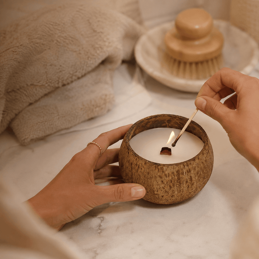 Hands lighting a Warmelle Coco Haven coconut shell candle