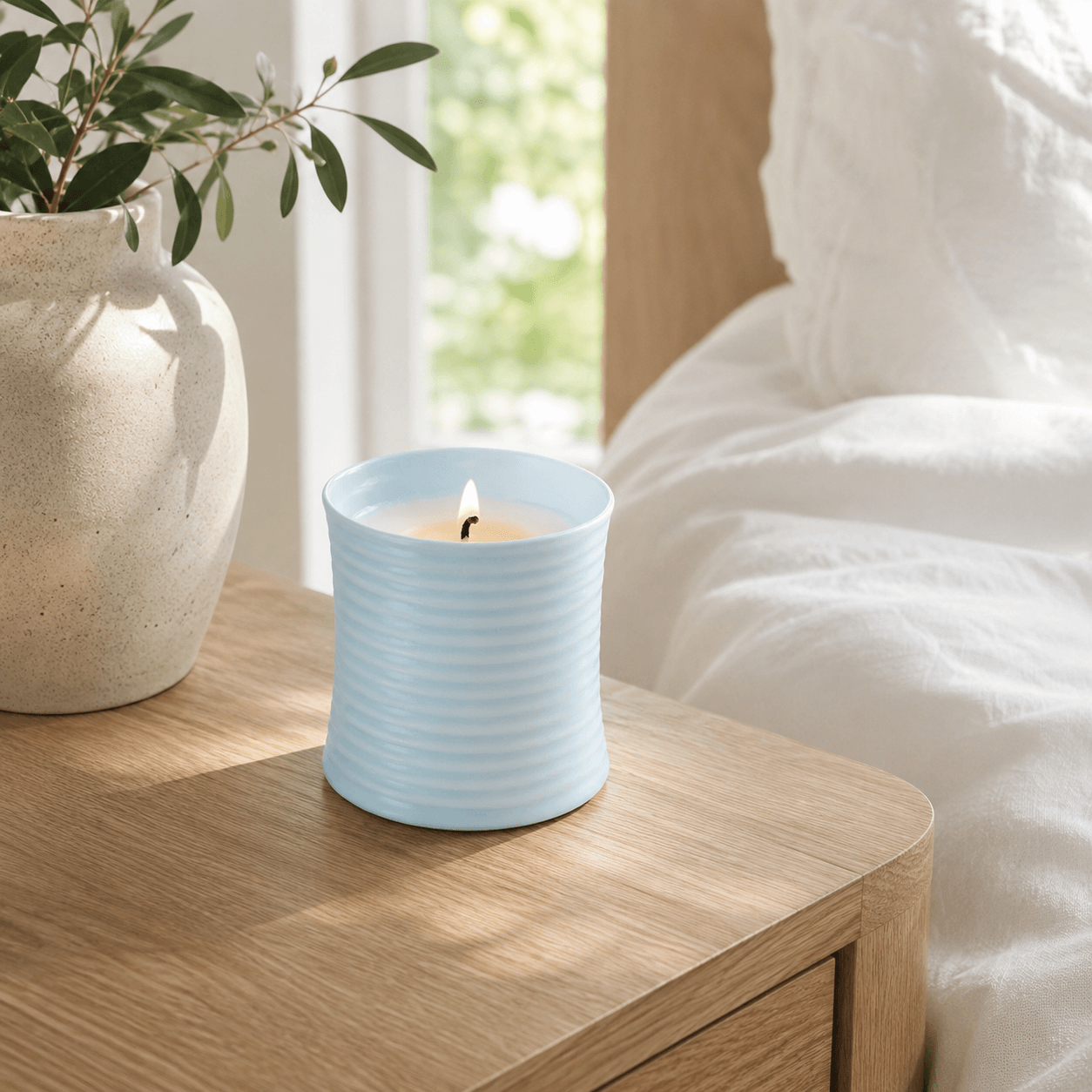Warmelle Riva light blue ribbed ceramic candle in a calm bedroom setting