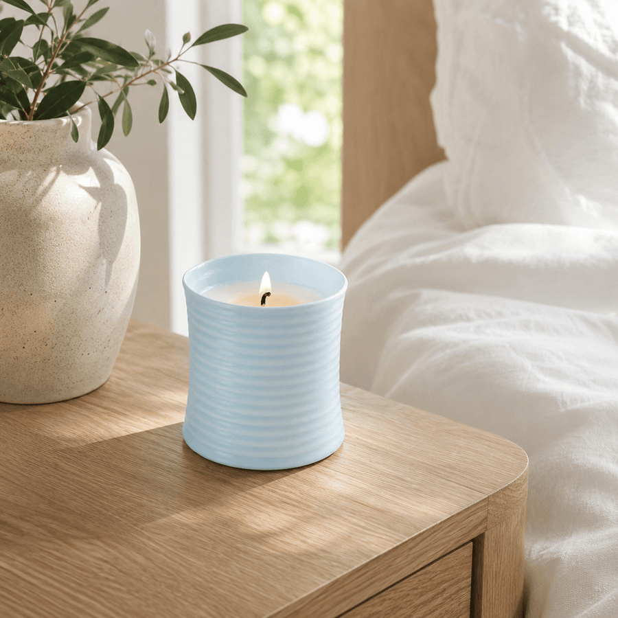 Warmelle Riva light blue ribbed ceramic candle in a calm bedroom setting