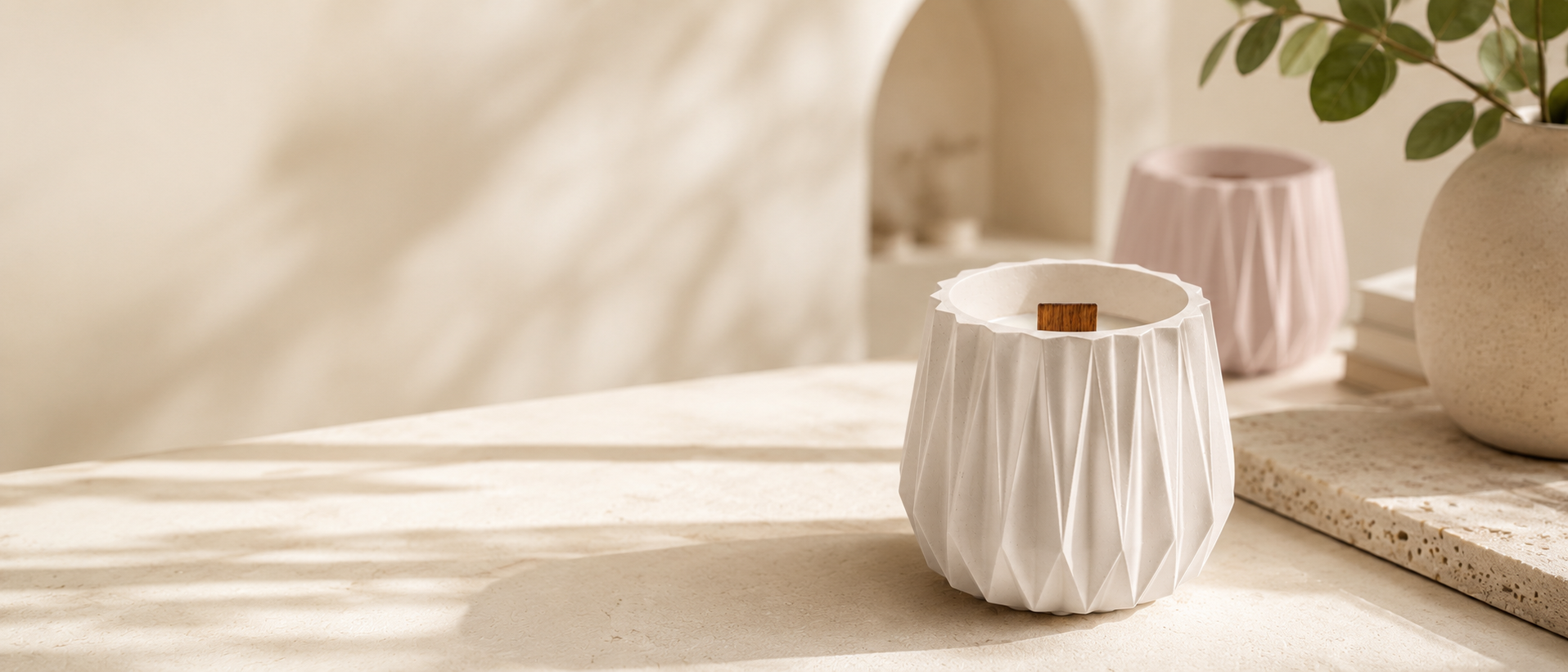 White origami-textured cement plaster scented candle with a natural wood wick in a warm minimalist interior